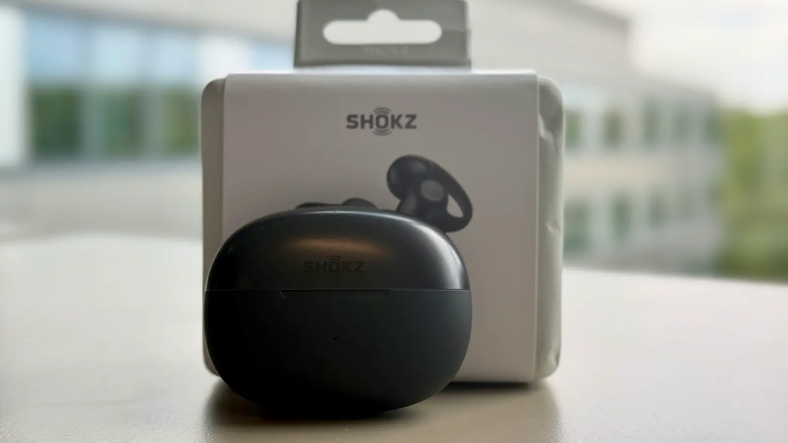 Boîtier de recharge des Shokz OpenDots 2 devant leur emballage