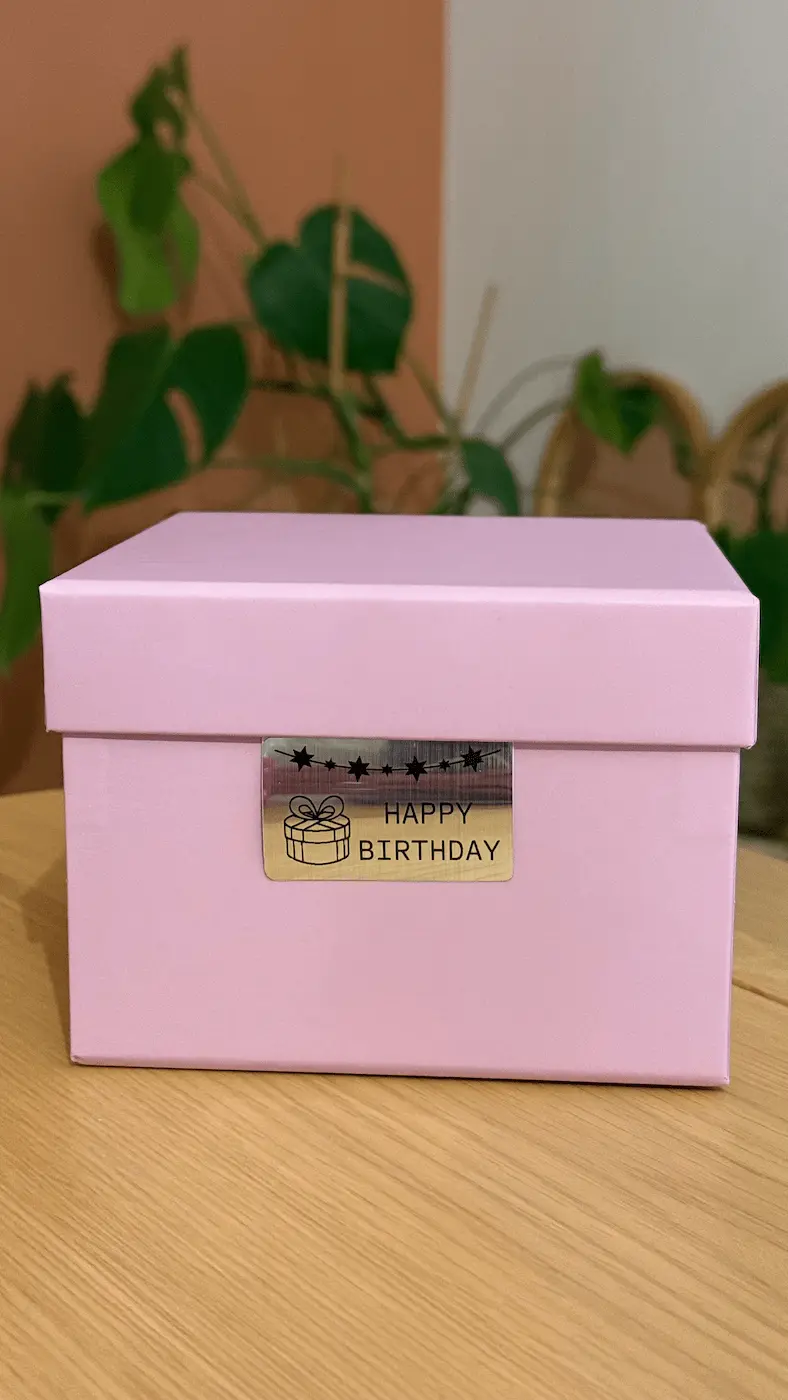 Boîte cadeau rose décorée d’une étiquette métallisée Happy Birthday