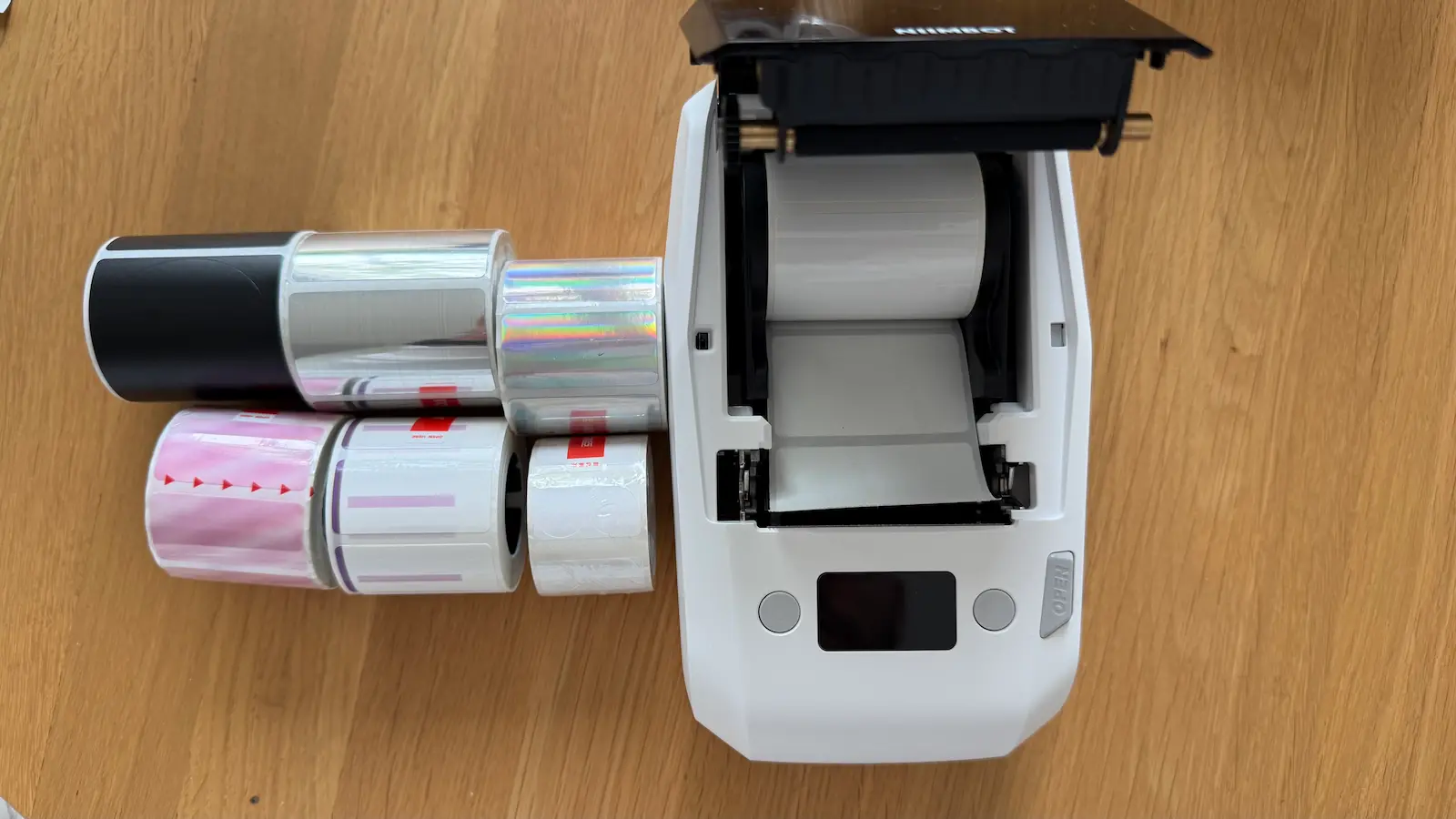 Compartiment ouvert de la NIIMBOT M2 avec un rouleau installé et plusieurs recharges à côté
